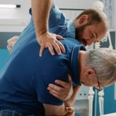 osteopath-helping-senior-man-crack-back-bones-cabinet-doing-physical-therapy-exercise-male-assistant-using-physiotherapy-procedure-increase-mobility-treat-patient (1)